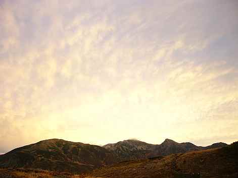 夕焼けに染まる雲、秋の山並みに映えての画像